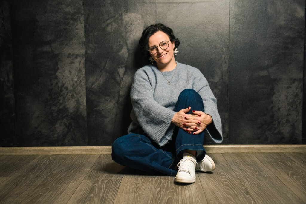 Sonja Sträßer sitzend, entspannt vor einer Schieferwand